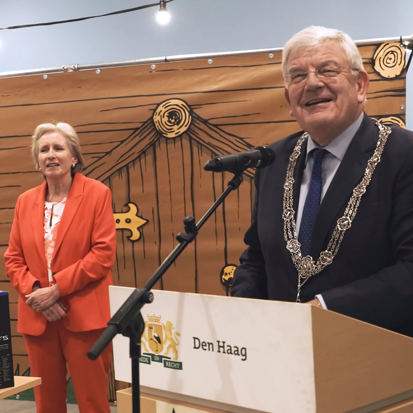 Burgemeester Jan van Zanen spreekt bij de prijsuitreiking van Verloot je Boompje; links staat Mendy van Veen, stadsdeeldirecteur van Scheveningen
